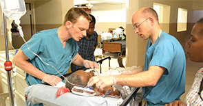 Joe Curry, MD, and Dr. Luginbuhl checking on a postoperative laryngectomy patient at the Hospital Lumiere in Bonne Fin, Haiti. 